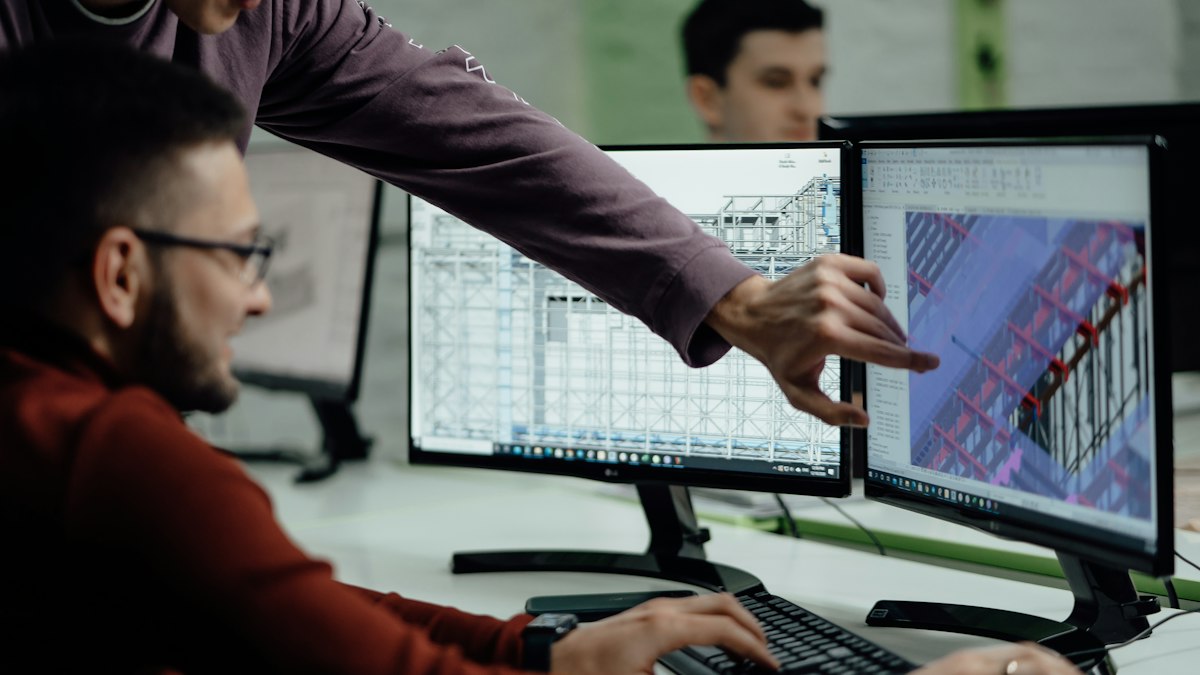 Colleagues in an engineering office reviewing building design plans together on a computer screen
