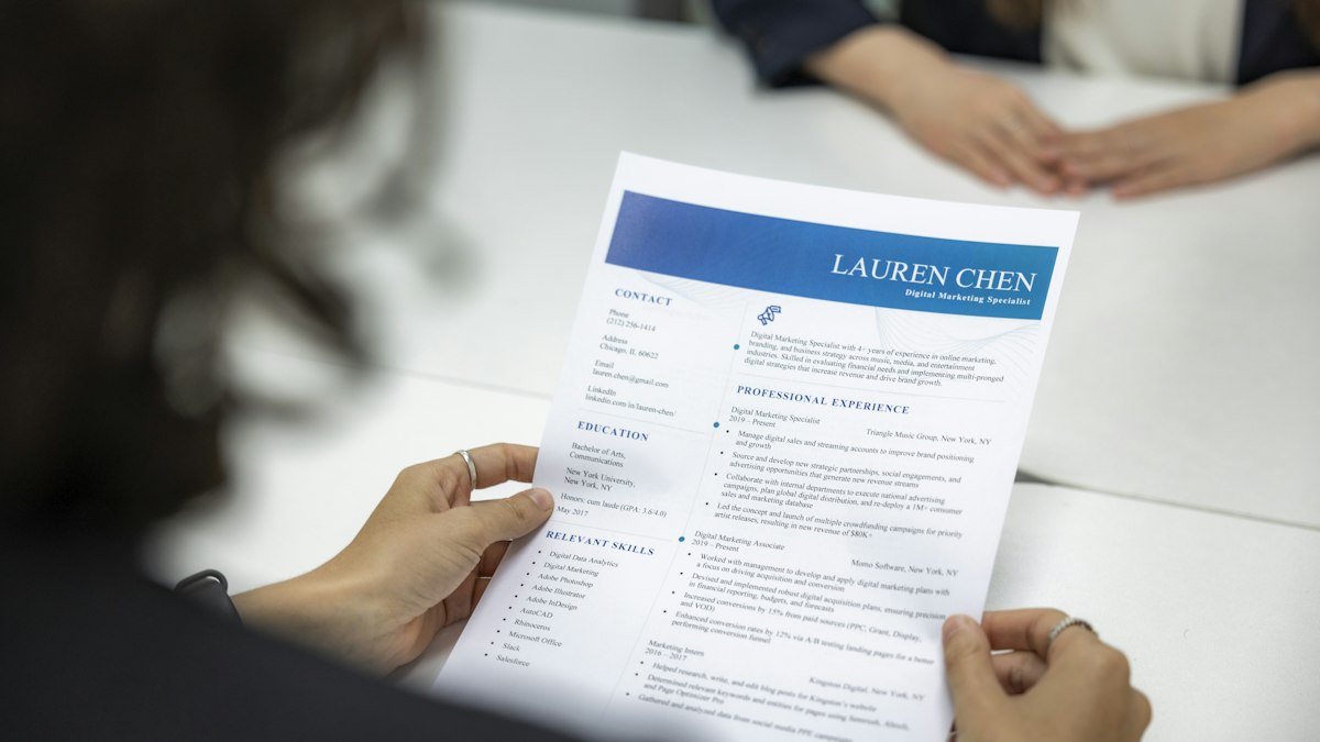 A woman reading a printed resume while seated at an office table