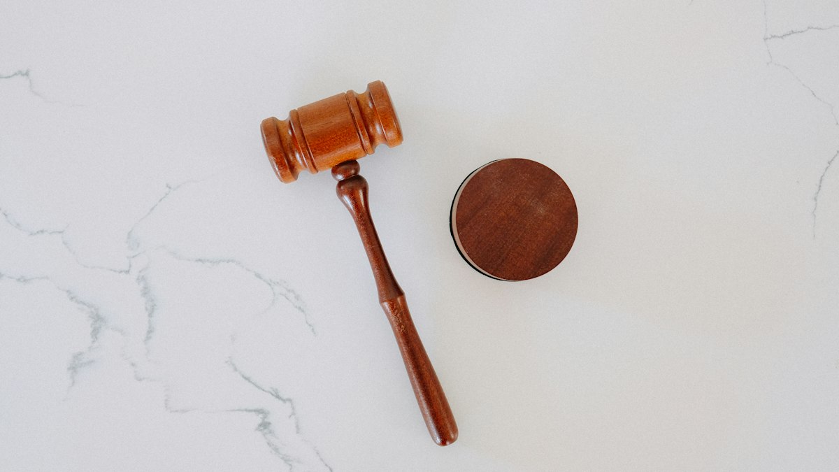 A wooden gavel resting on a desk next to an open laptop displaying a chat conversation