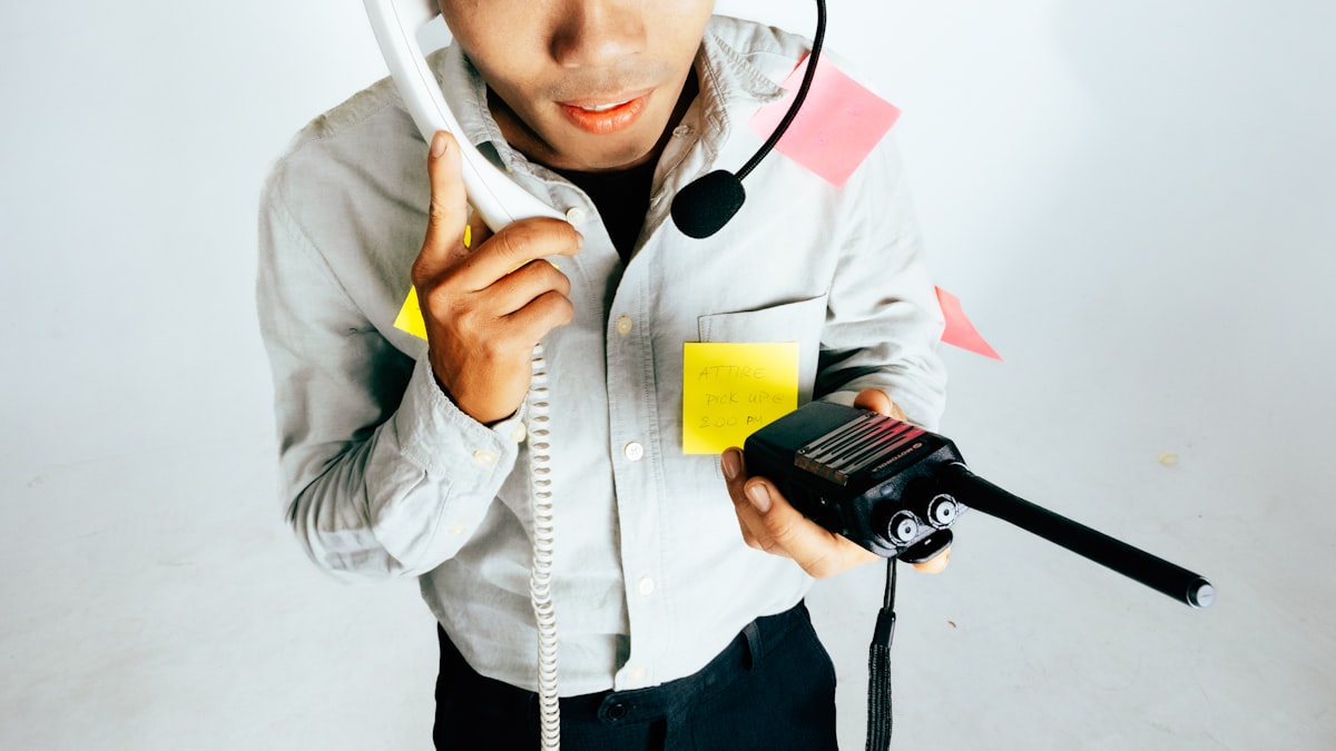 A person at a desk juggling a phone call while working at a computer, representing the moment a business either answers a call or lets it go to voicemail