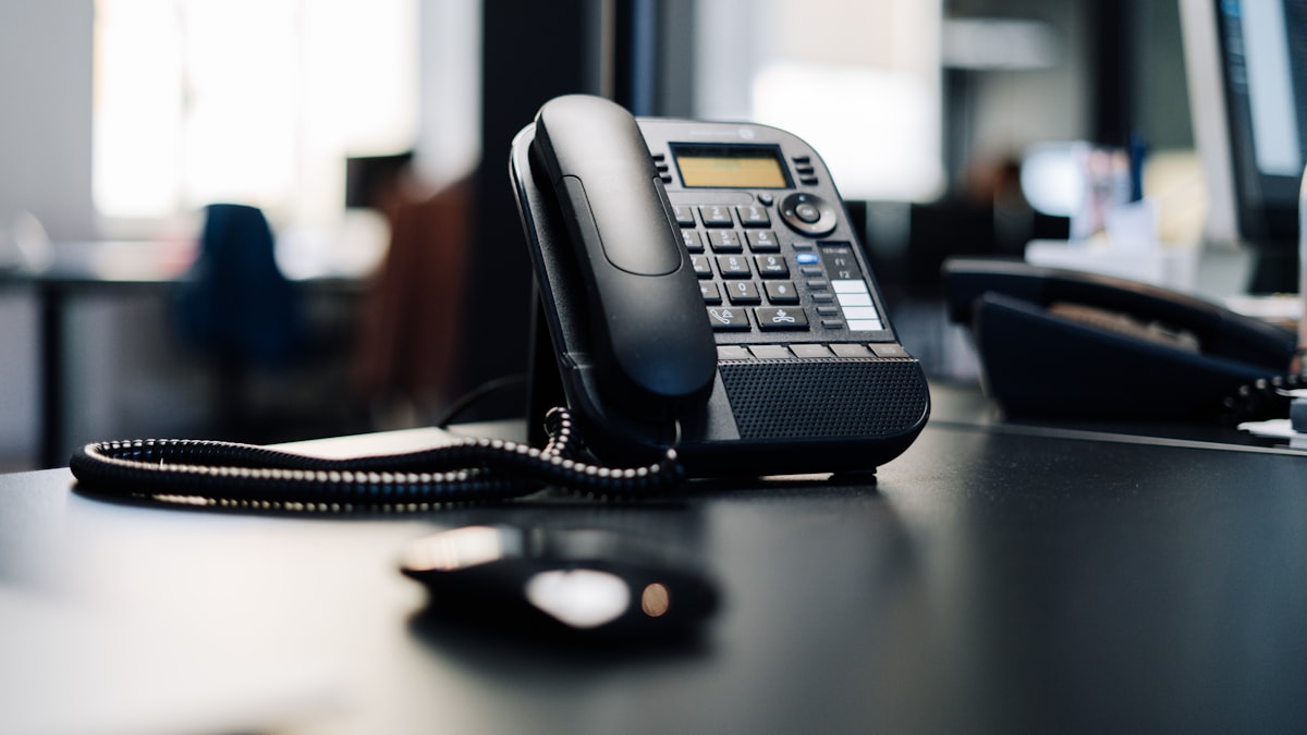 A business phone sitting on a desk with its coiled cord, the kind of line an auto repair shop uses to take booking and quote calls