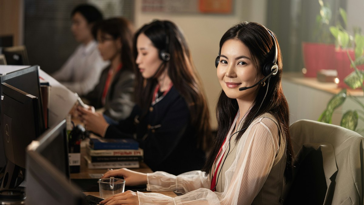 A person wearing a headset while working at a computer, taking a call