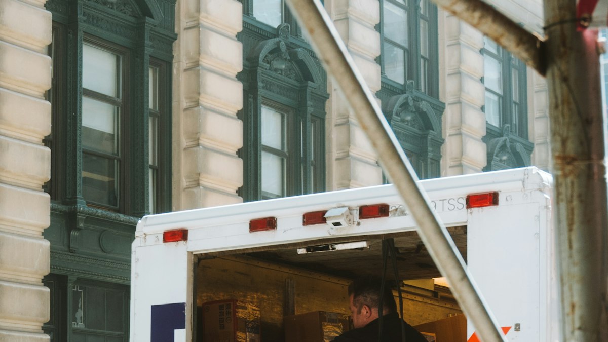 A man loading cardboard boxes into the back of a moving truck