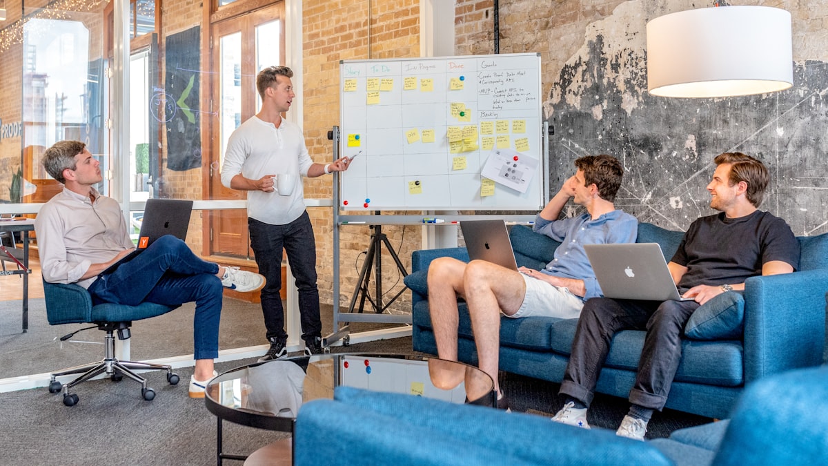 A team of developers standing around a whiteboard covered in diagrams, planning a software project together